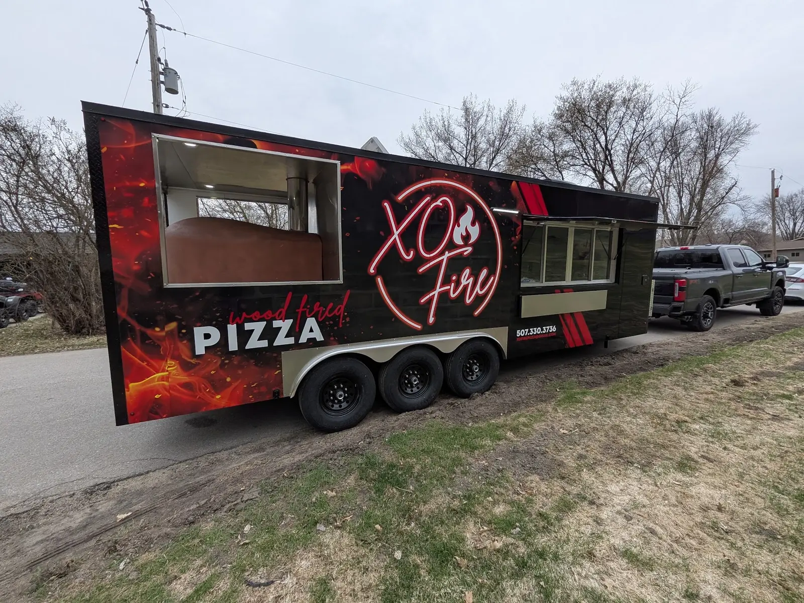 Black and red fire-themed pizza trailer wrap viewed at an angle